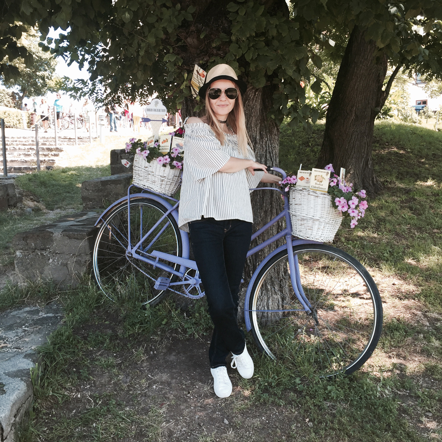 off-shoulder striped top, indigo slim straight jeans, white trainers, straw trilby, Nineties nylon choker, aviators, lavender bicycle