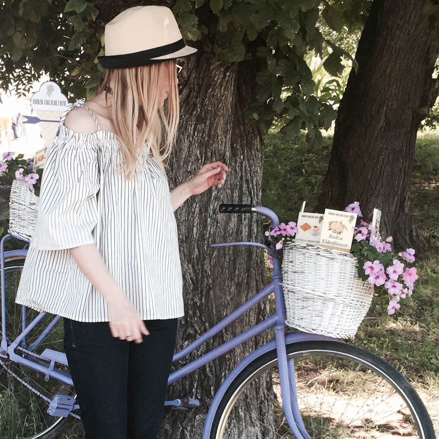 off-shoulder striped top, indigo slim straight jeans, white trainers, straw trilby, Nineties nylon choker, aviators, lavender bicycle