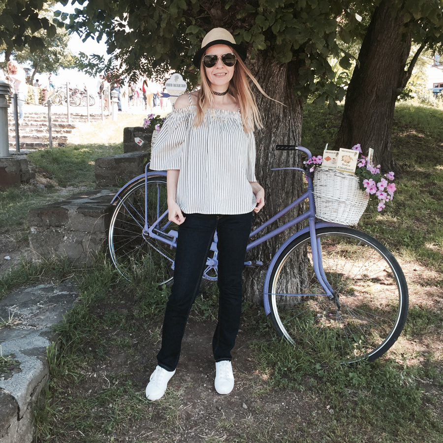 off-shoulder striped top, indigo slim straight jeans, white trainers, straw trilby, Nineties nylon choker, aviators, lavender bicycle